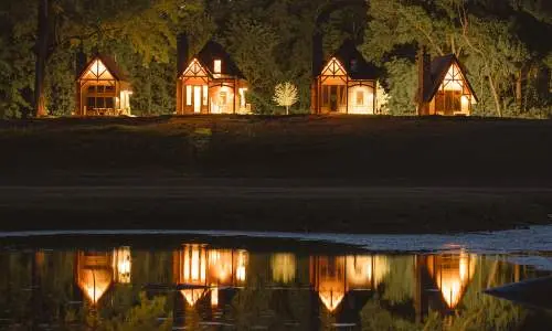 夜、ライトアップされた4つのキャビンが水面に映る