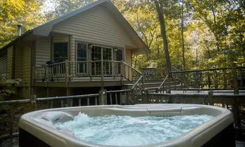 木立に囲まれた小屋の前にある、泡の出る湯船