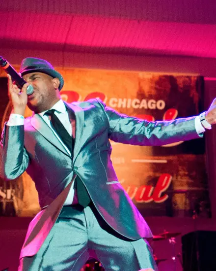 上品なメタリックスーツを身にまとい、ステージで歌を口ずさむブルース・シンガー。