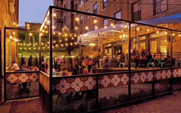 電球色の照明の下、屋外のパティオで食事をする客たち