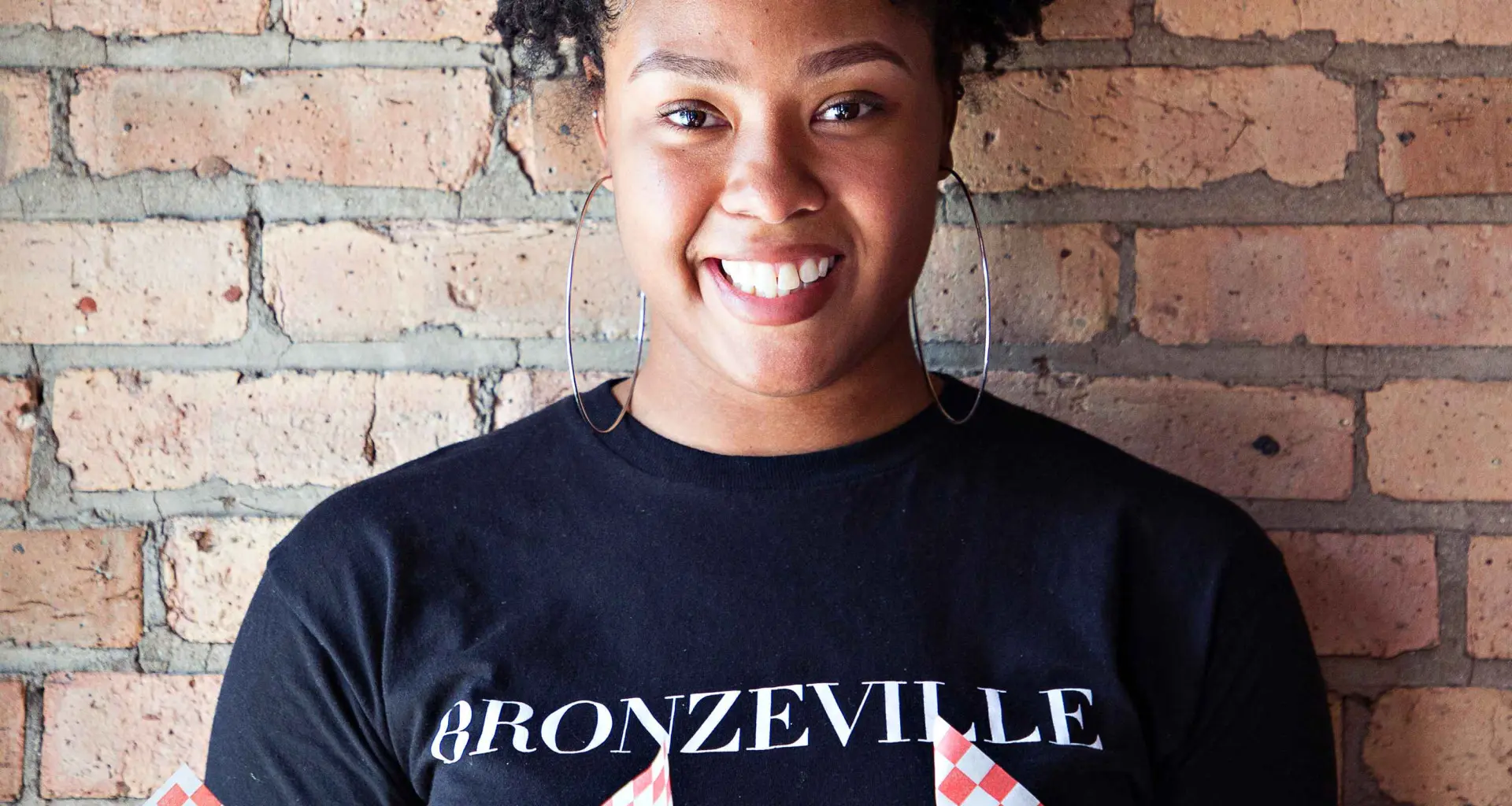 レンガの壁の前で食べ物を手にする女性