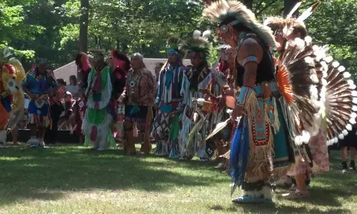 木々が生い茂る草原で、ネイティブ・アメリカンの衣装をまとった男たち。