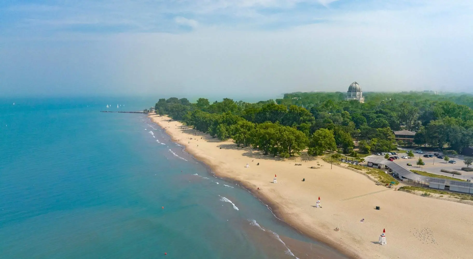 緑の木々を背景にビーチの海岸線を空撮。