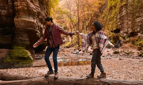 秋の森をハイキングするカップル。