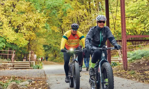 古い木橋の下の林道を走る2人のサイクリスト