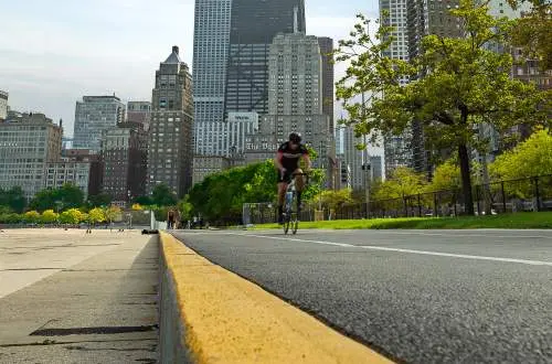 道路を自転車で走る男の背後にある街
