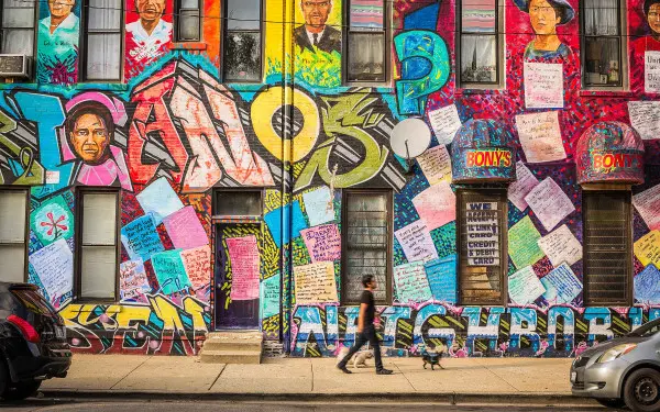 メキシコ文化遺産の壁画の前を歩く犬を連れた人