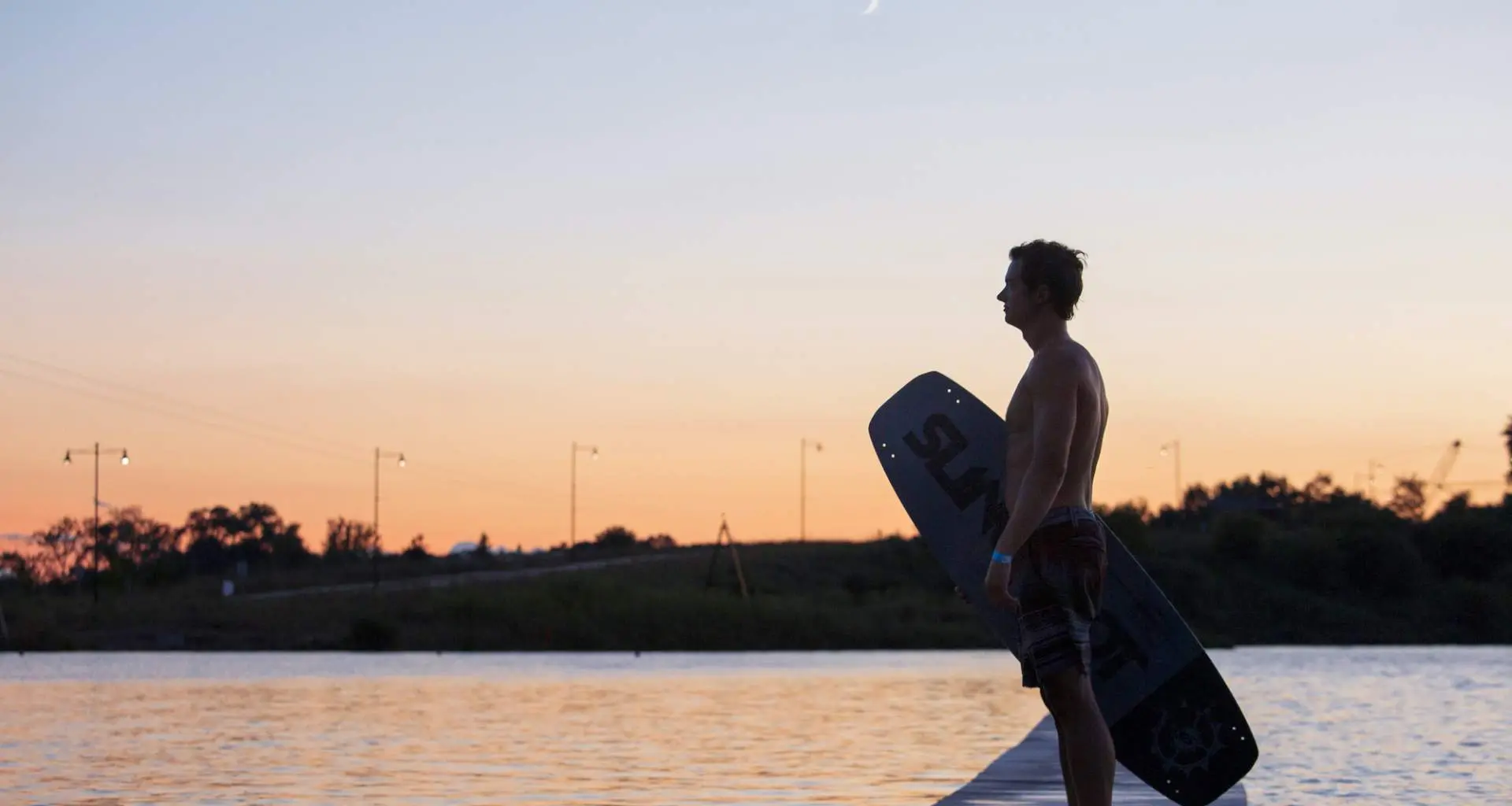 夕暮れのクオリーケーブルパーク横に立つウェイクボーダー