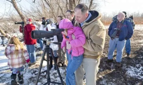 大きなカメラのレンズを覗く人々