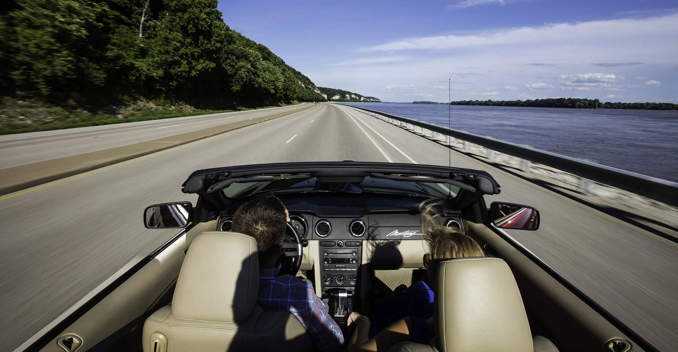 屋根のない車で道路を走る2人