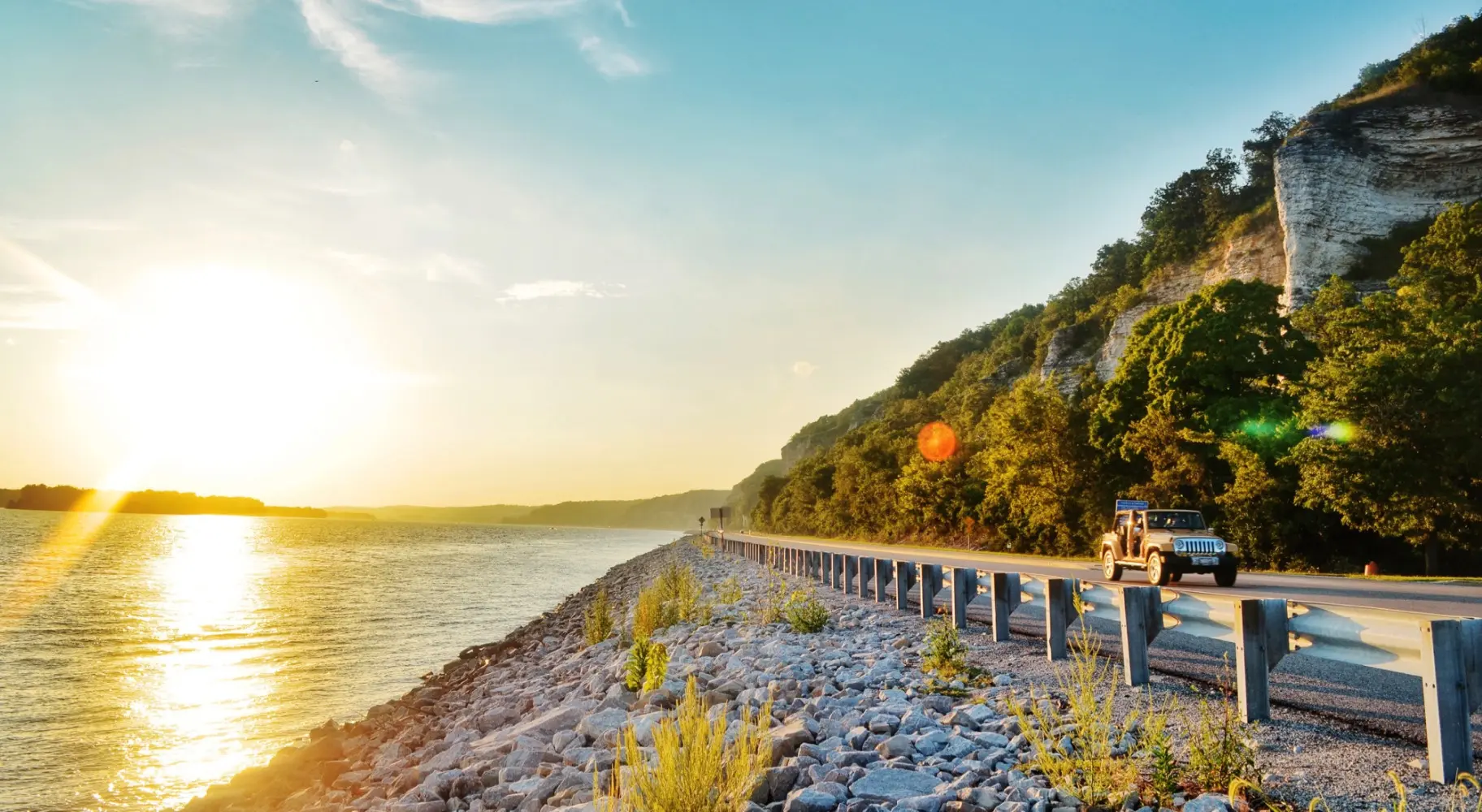 水面から昇る朝日と、その横を走る車。
