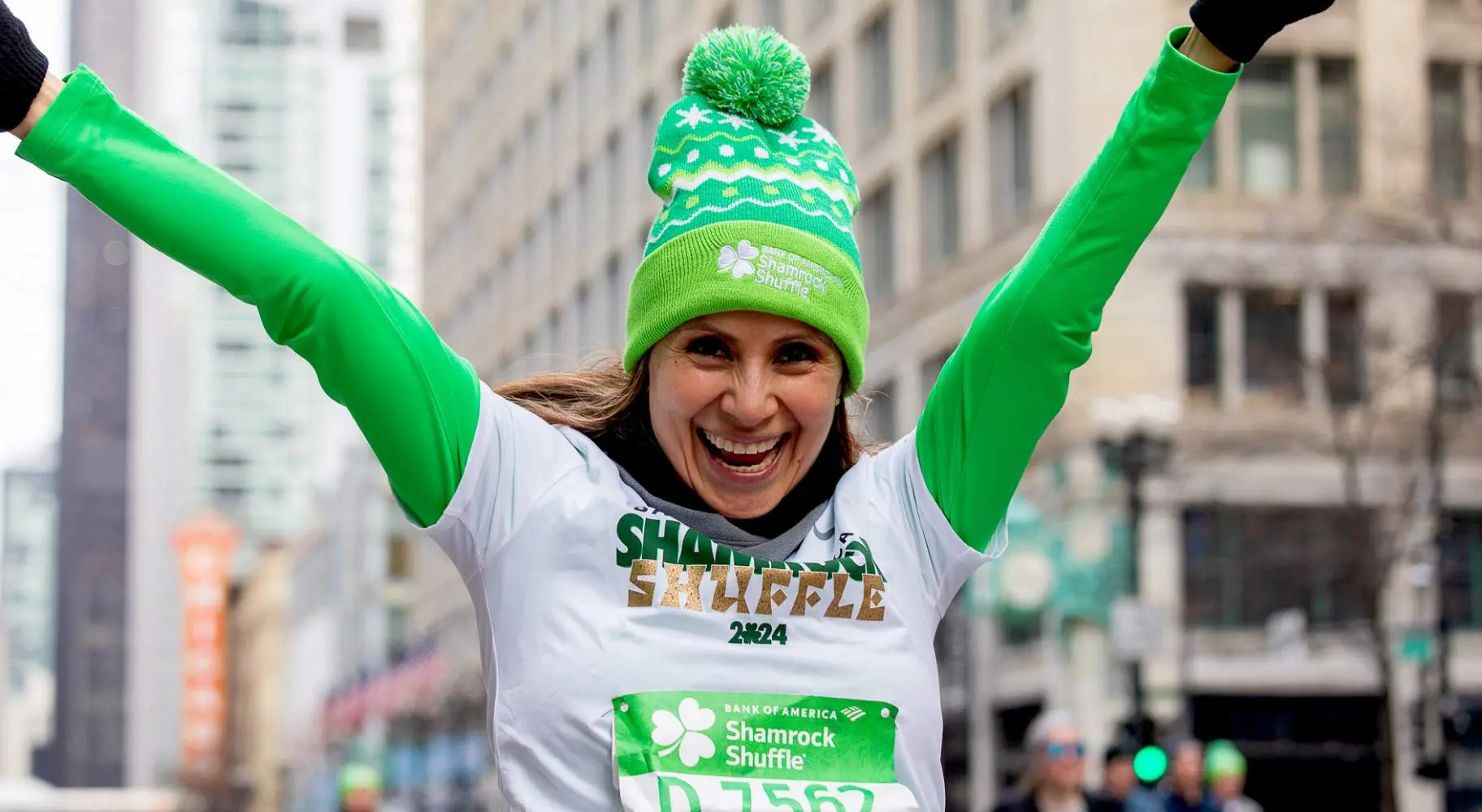 緑色の服を着て両腕を上げたランニング・レース参加者